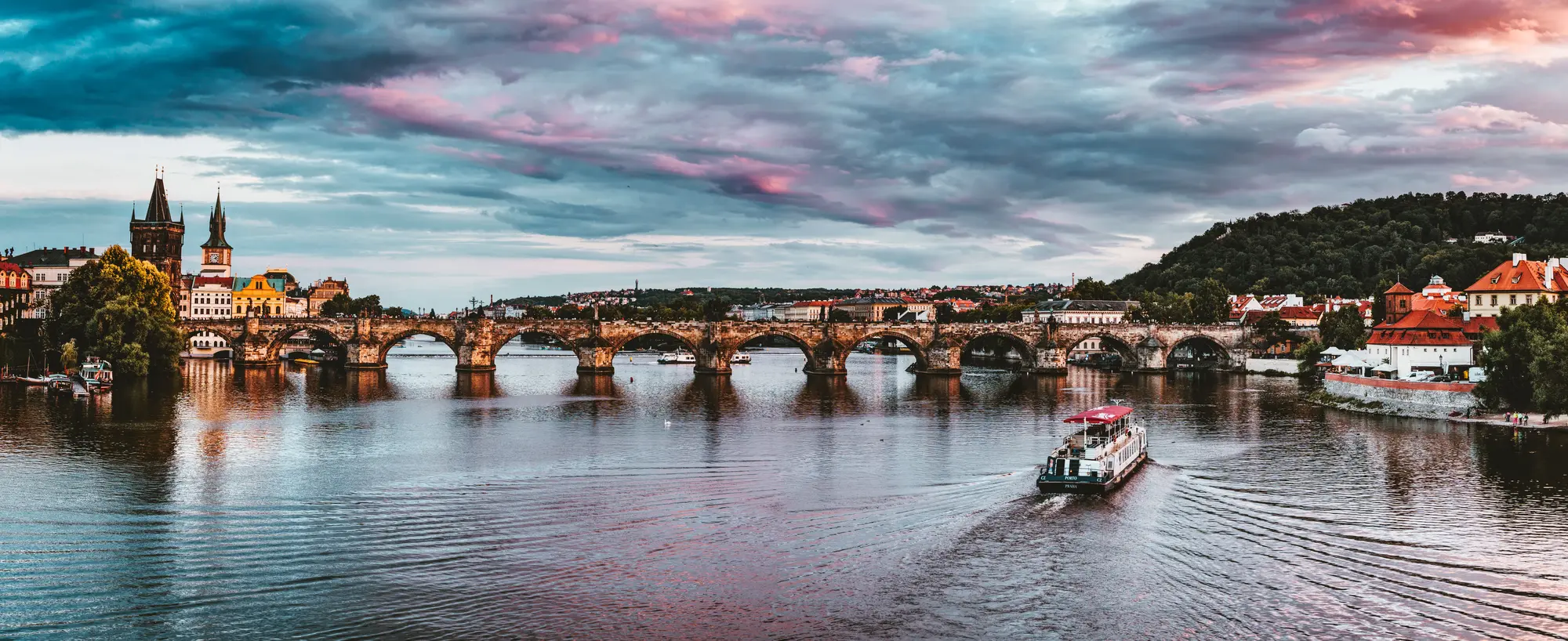Karlův most přes Vltavu pod dramatickou oblohou